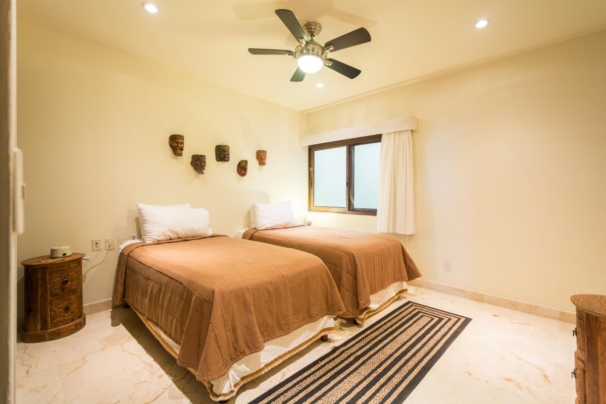 Beachfront condo for sale in Playa del Carmen – bedroom with two beds and both natural and artificial lighting