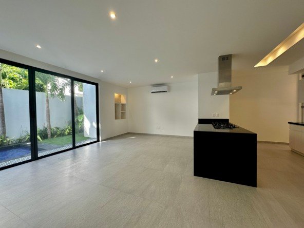 House for sale on Huayacan Avenue – spacious living room with large sliding glass windows overlooking a swimming pool