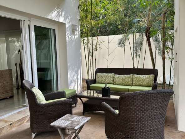House for sale in Lagos del Sol, Cancun – cozy outdoor space with dark wicker furniture surrounded by palm trees