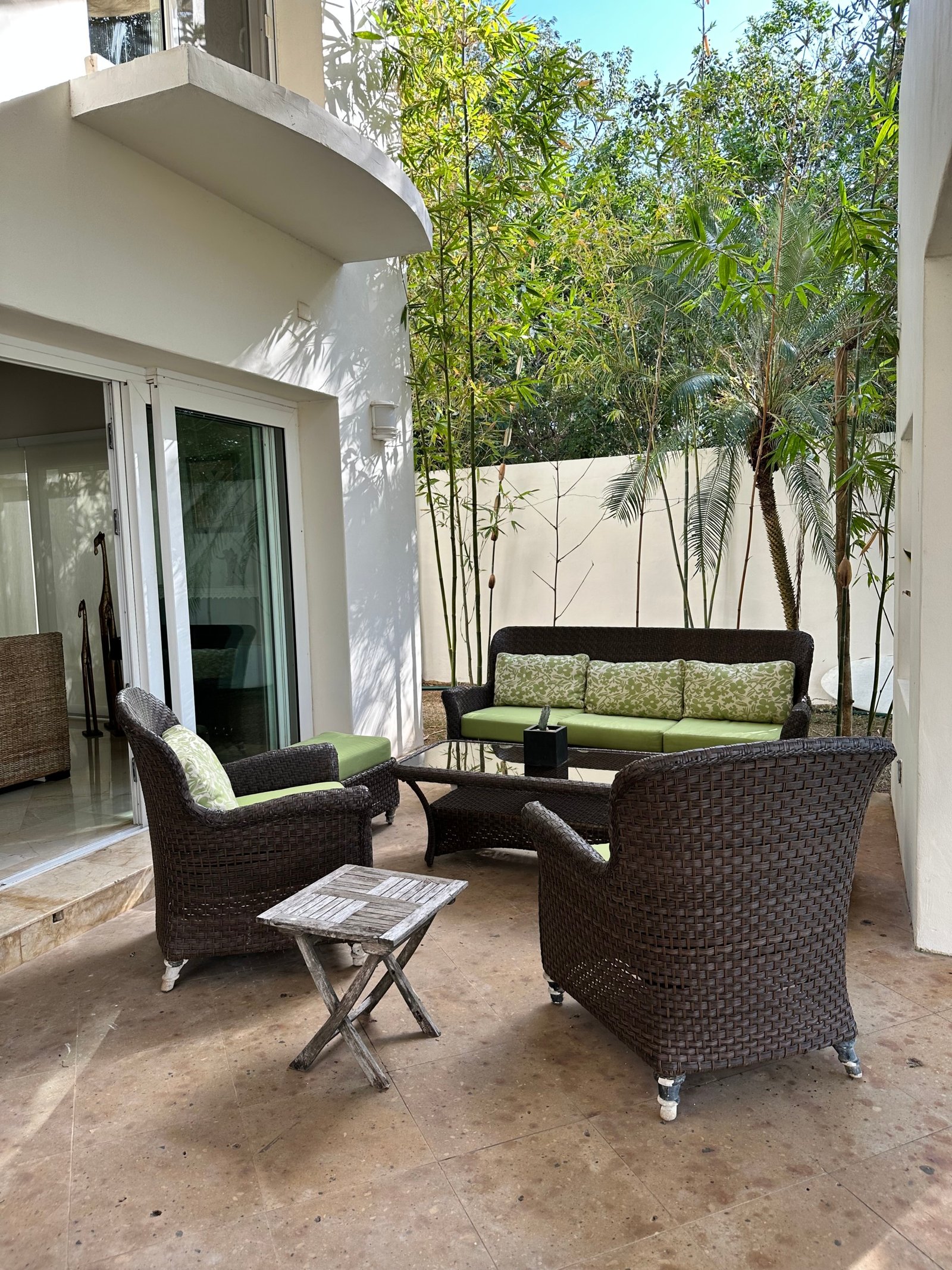House for sale in Lagos del Sol, Cancun – cozy outdoor space with dark wicker furniture surrounded by palm trees