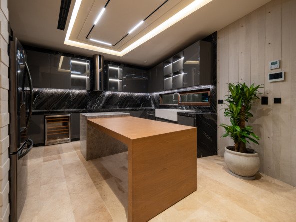 House for sale in Puerto Cancún - kitchen with central island, black marble countertops and contemporary ceiling lighting