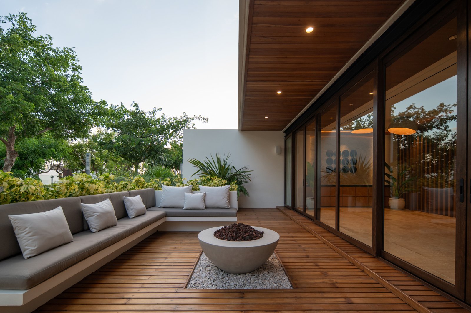 House for sale in Puerto Cancún – expansive outdoor terrace with hardwood flooring, an L-shaped sofa, and a sleek central fire pit