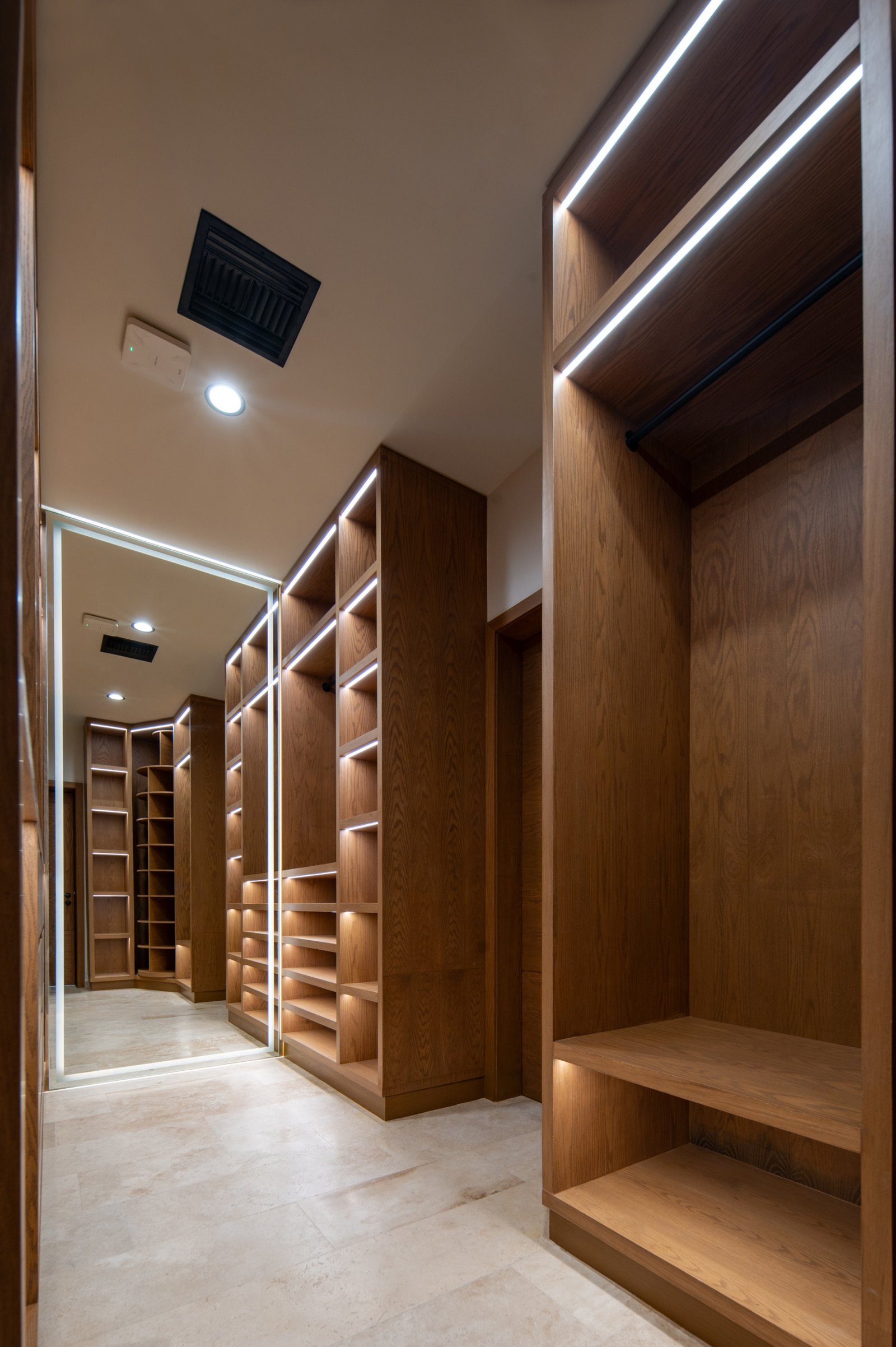 House for sale in Puerto Cancun – Walk-in closet with spacious wooden shelves and drawers, lit by built-in LED lights