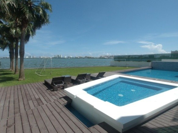 House for sale on Isla Dorada, Cancún – pool with lagoon view and hotels in the background