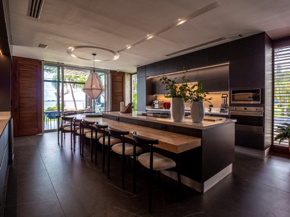 House for sale Isla Dorada Hotel Zone Cancún – kitchen bar, at the back the full kitchen with dark details