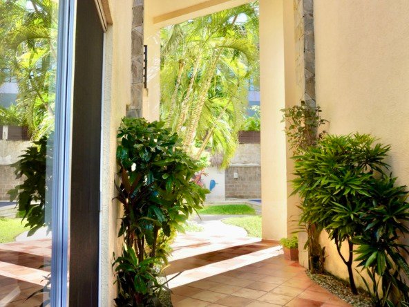 Condo for sale in downtown Cancun – Exterior entrance with vegetation and view of a tropical garden with palm trees