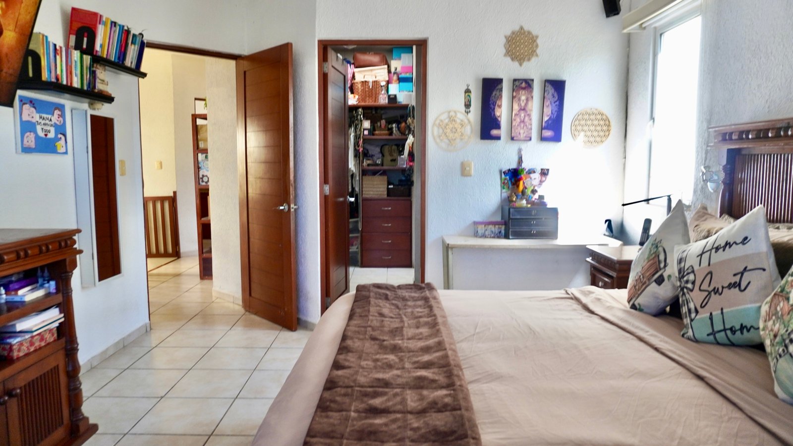Apartment for sale in downtown Cancun – Bedroom with a large bed and traditional wooden furniture. A walk-in closet is visible.