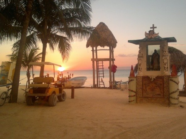 Land for sale on Holbox Island – Sunset beach with palm trees, golf cart, and watchtower facing the sea