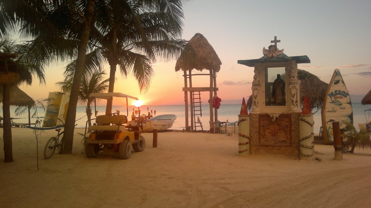 Land for sale on Holbox Island - Beach at sunset with palm trees, golf cart and watchtower by the sea